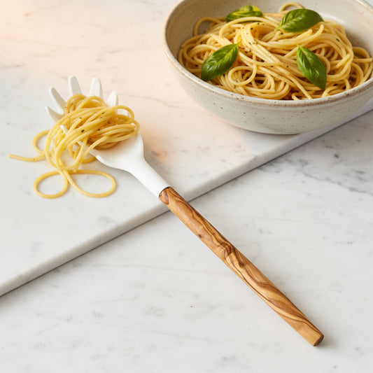 A spaghetti server with an olive wood handle and a white silicone head with pasta-shaped openings.