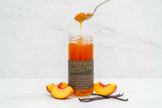 Jar of peach shine moonshine and vanilla bean jam with a spoonful being poured out.