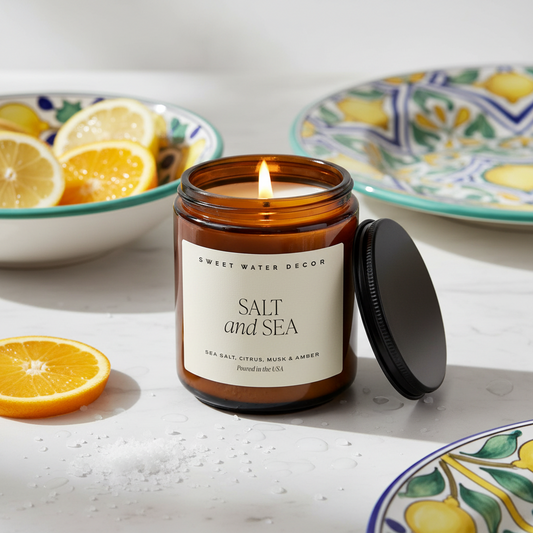 Candle in a brown jar with a label reading 'Sweet Water Decor Warm and Cozy' on a white background.