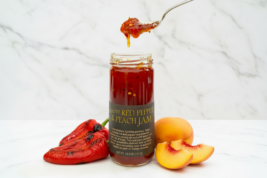 Jar of roasted red pepper and peach jam with a spoonful of jam above it on a white background