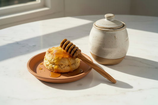 An olive wood honey dipper with a metal handle.