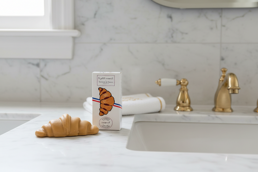 Croissant-shaped soap with packaging featuring a croissant illustration on a white background