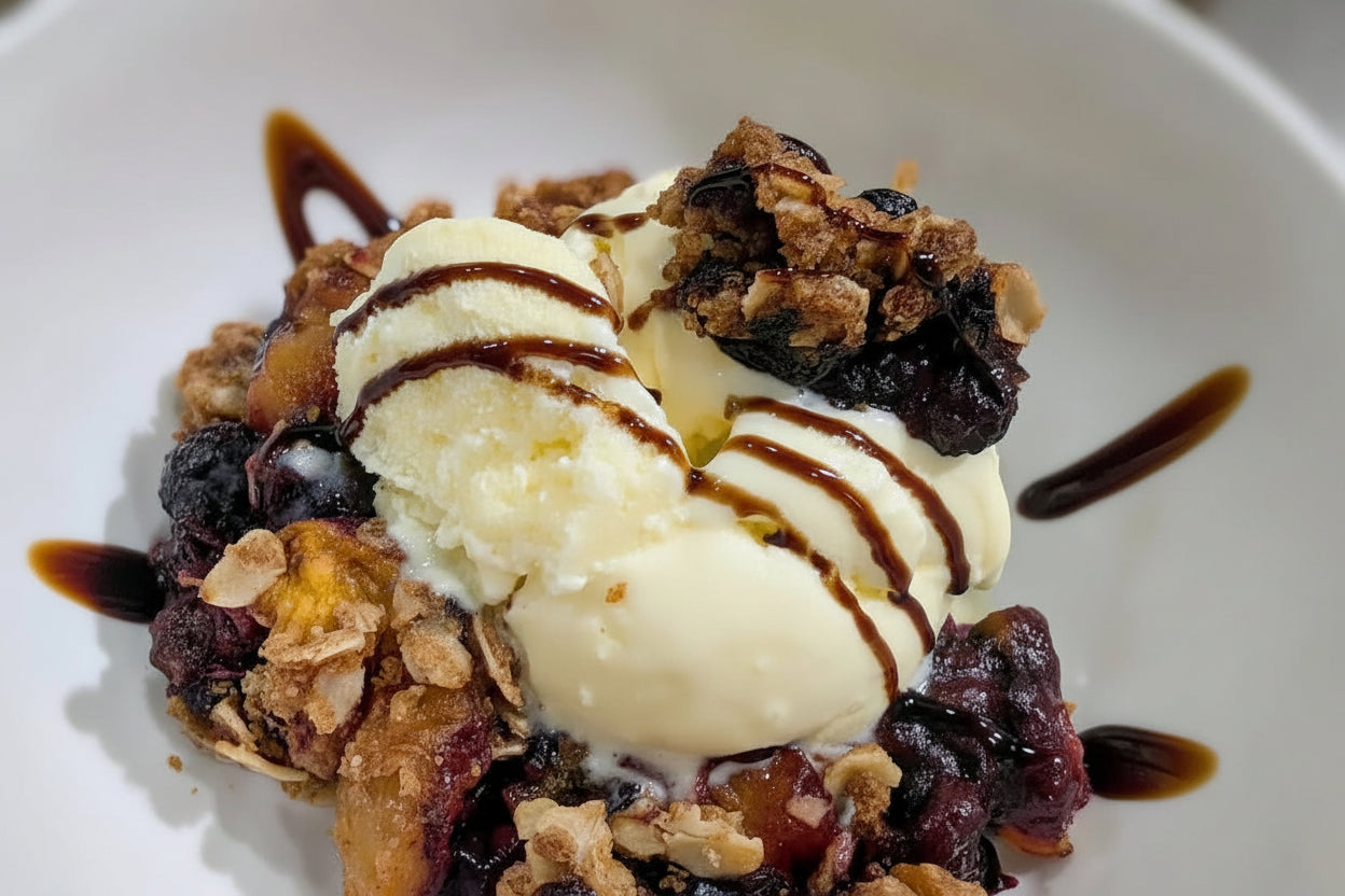 Blueberry crisp with vanilla ice cream on a white plate