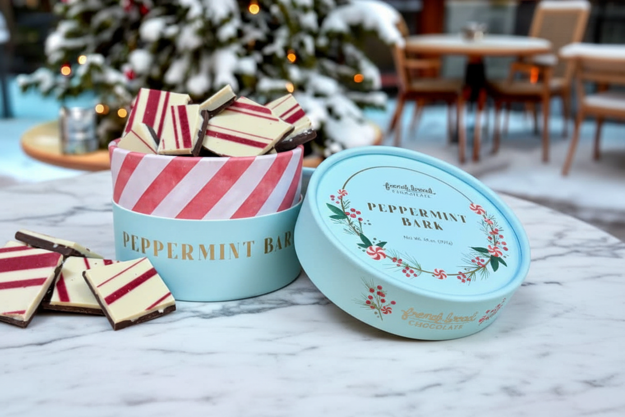 Two containers of peppermint bark on a table with a festive background